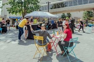 People enjoying drinks and conversation at colorful tables on a sunny day in the lively Encore Terrace at RBC Place London