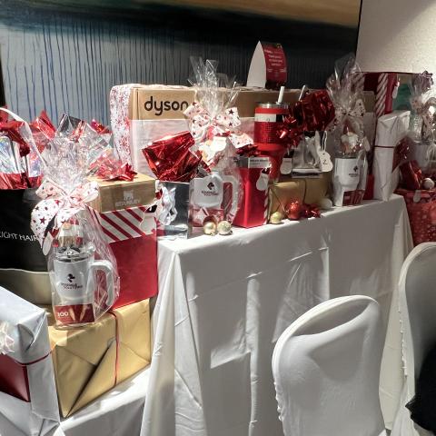 Door prizes, wrapped in red, gold, and white paper and ribbon for Christmas at our Place event.
