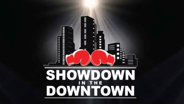 Two red boxing gloves in front of a city skyline with bright light shining above and the text 'Showdown in the Downtown'.